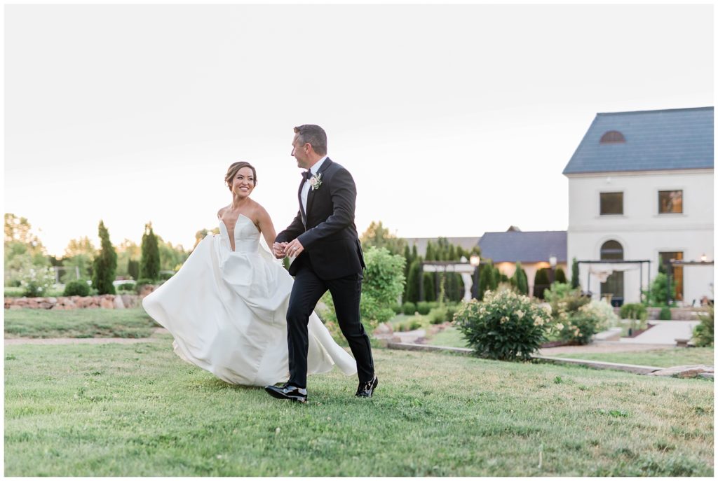 bride and groom running through field on wedding day