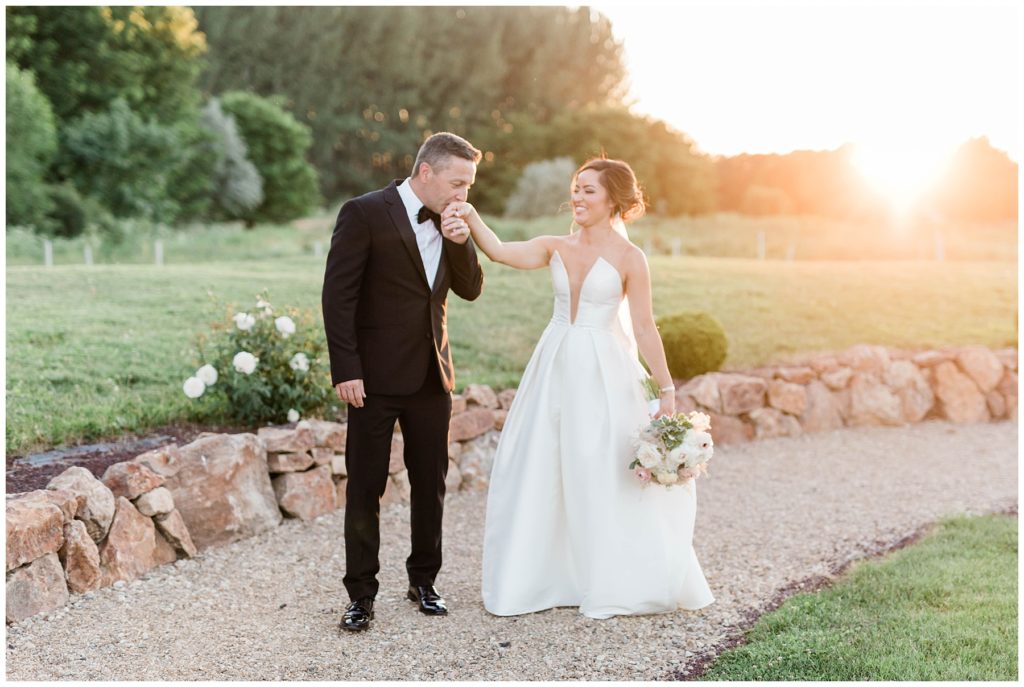 bride and groom walking around during bridals at golden hour kissing her hand