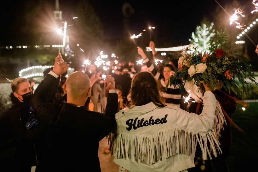 bride and room leaving whimsical still water hollow wedding during sparkler exit with bride wearing fringe jacket
