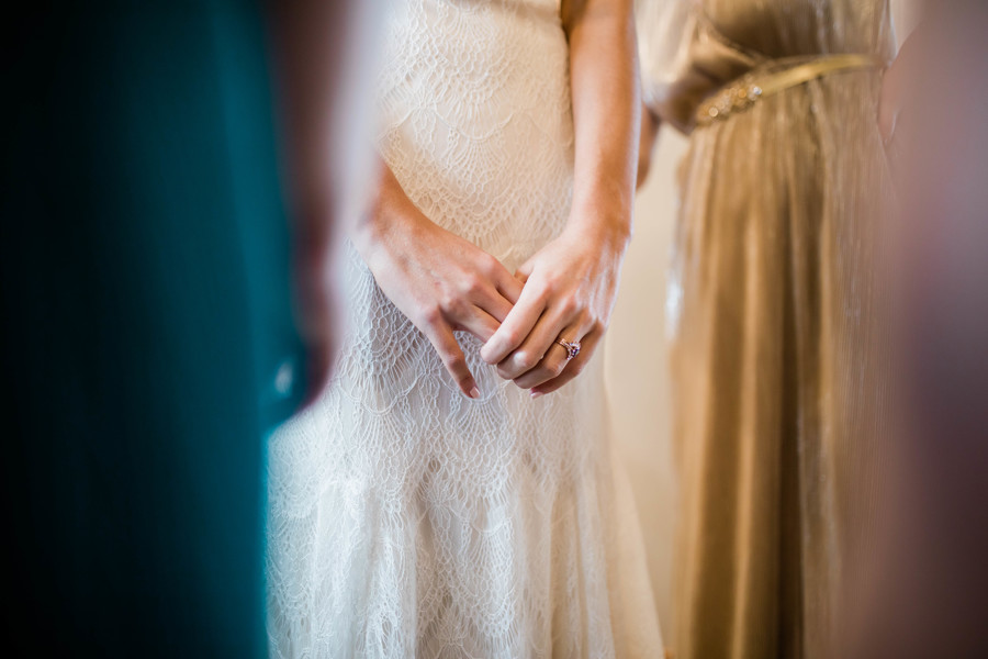 bride holding hands while getting dress on