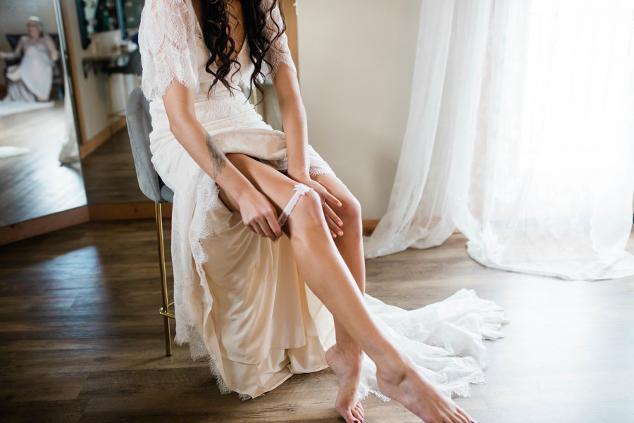 bride placing garter on leg 
