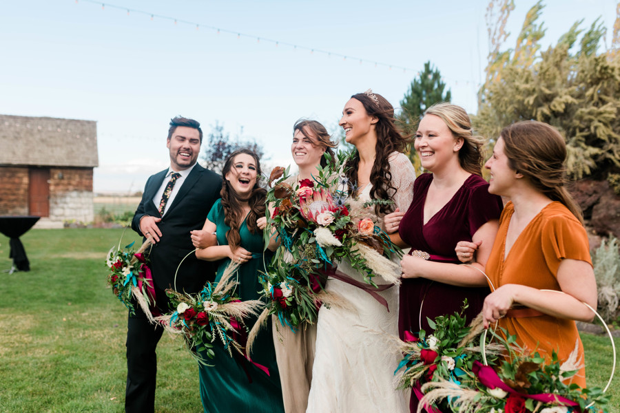 bride walking with bridesmaids in fall colored dresses laughing together