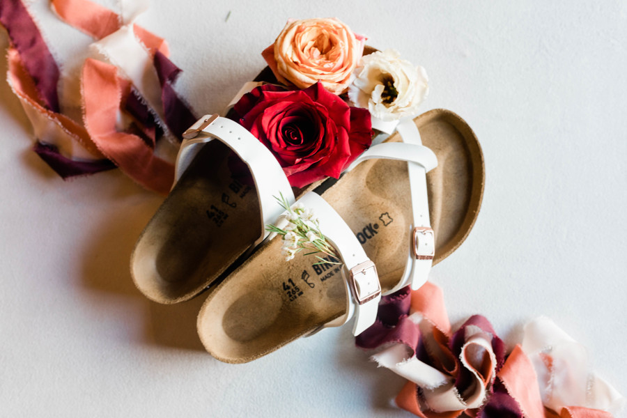bridal shoe detail shot of white birkenstocks with flowers sitting on footbed