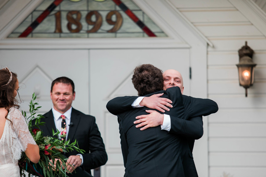 groom hugging bride's father on wedding day