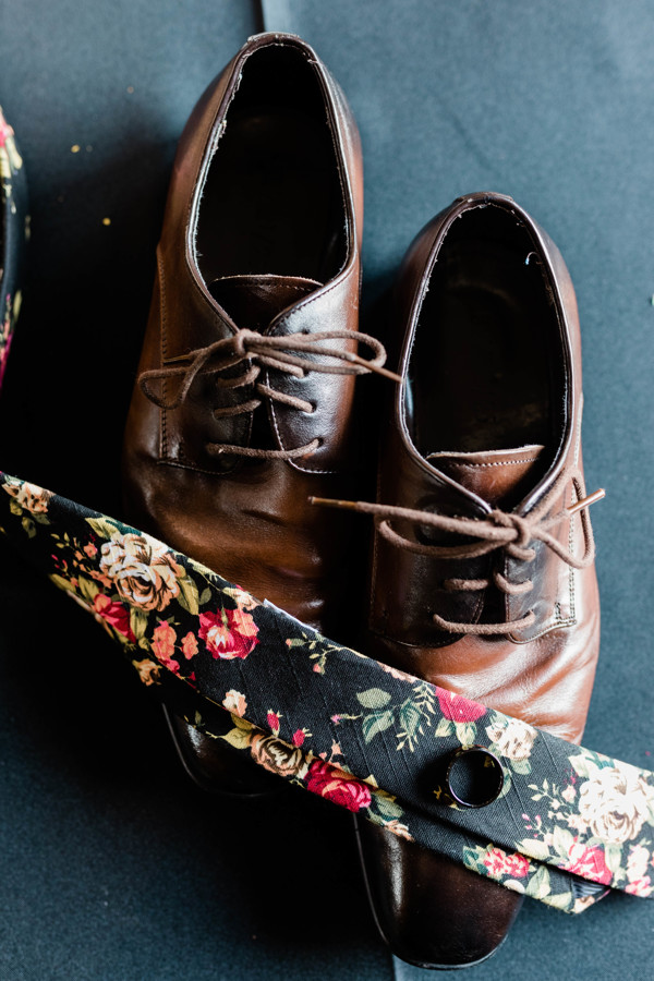 groom's shoes with floral tie on top