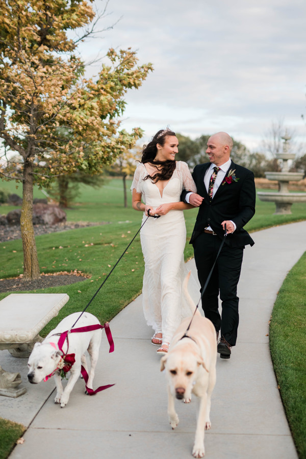 bride and groom walking with pups on wedding day