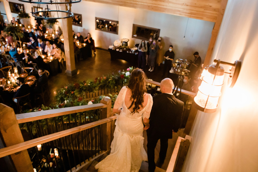 bride and groom entering their wedding reception as they walk down a set of stairs