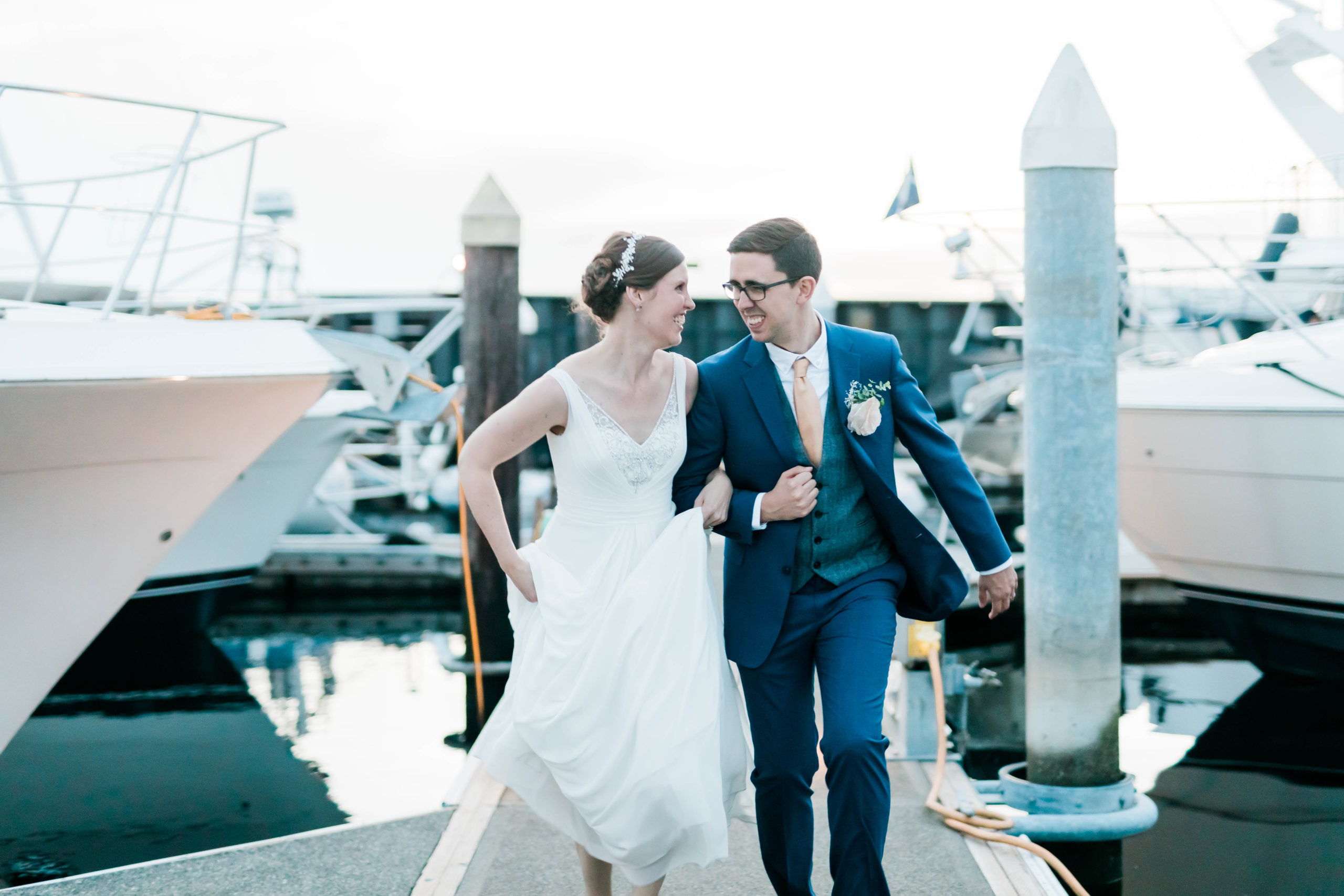 bride and groom running on marina during nautical wedding inspiration