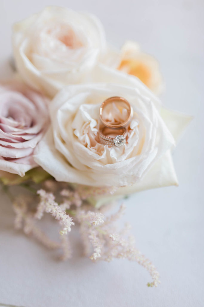 detail shot of brides rings on top of white roses