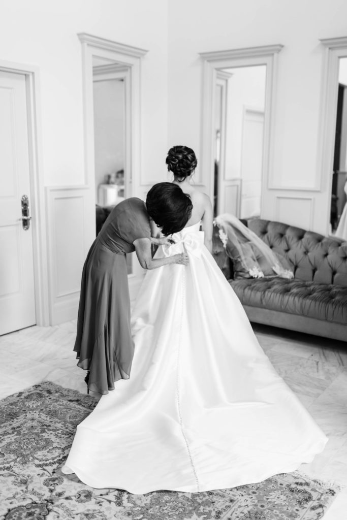 mother buttoning her brides gown in a bridal room 