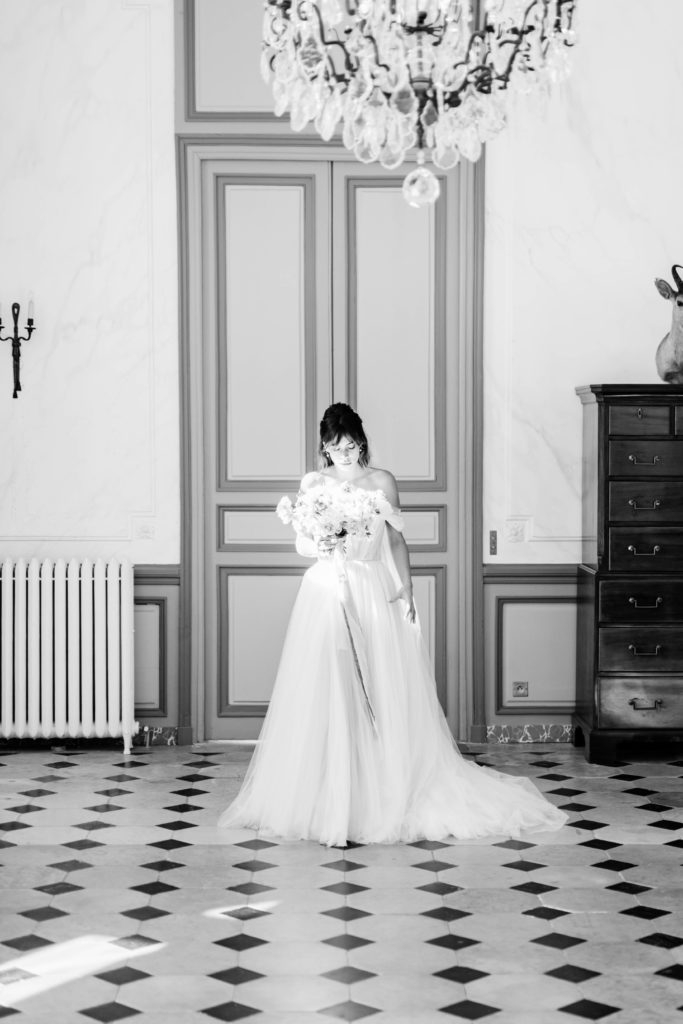 black and white image of a bride walking the camera in a tulle wedding dress in an elegant mansion