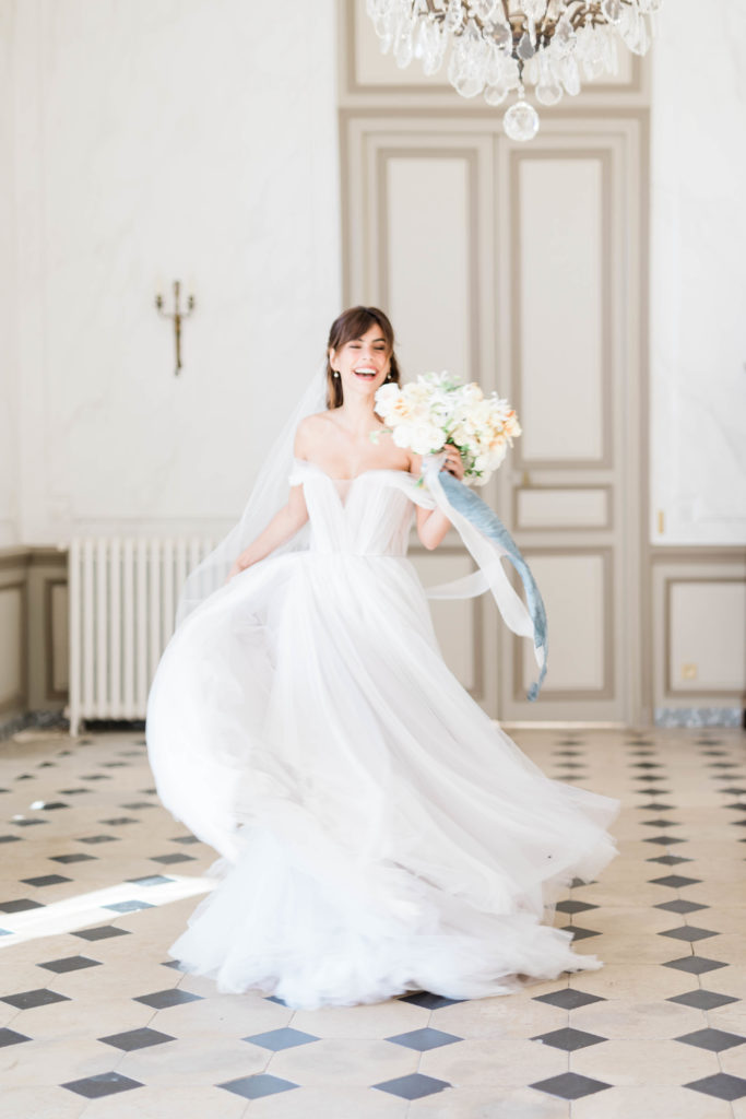 dancing bride in a beautiful tulle deep v wedding gown while she holds a white wedding bouquet