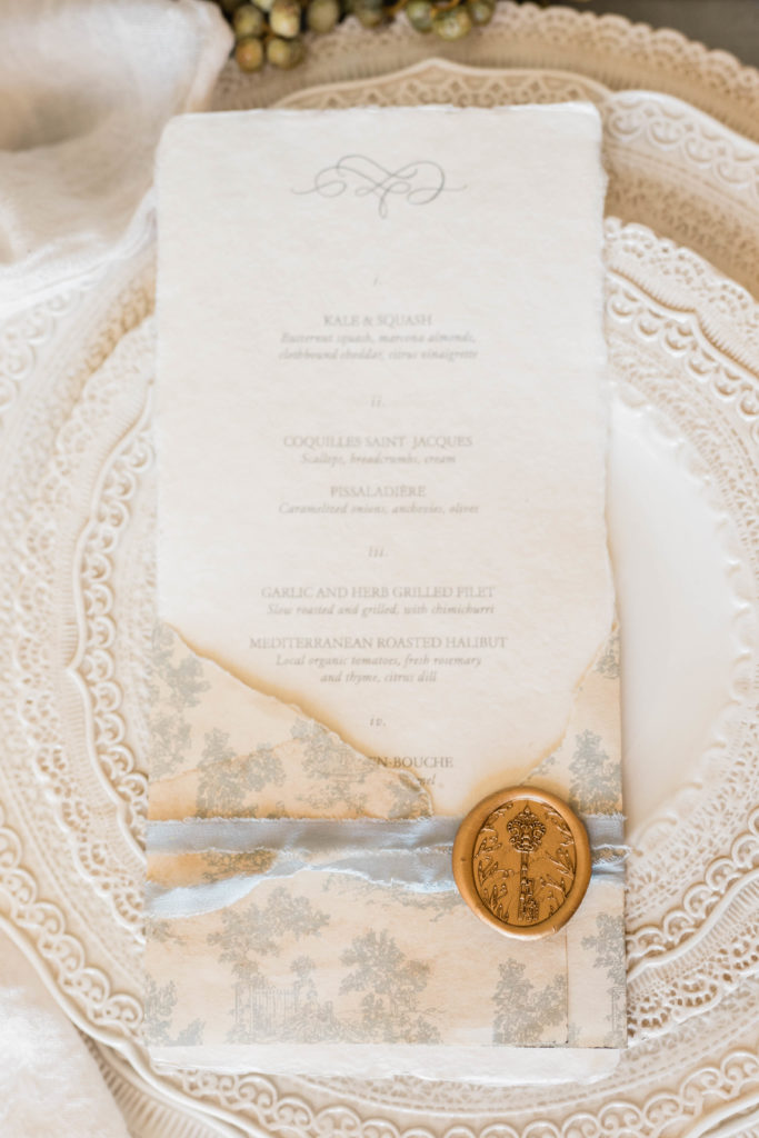 elegant wedding invitations with a gold wax stamp on the table setting