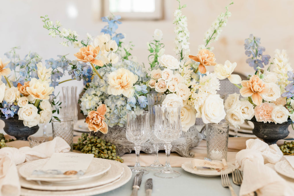 pastel florals arranged on a formal wedding table settings with crystal glasses and white plates