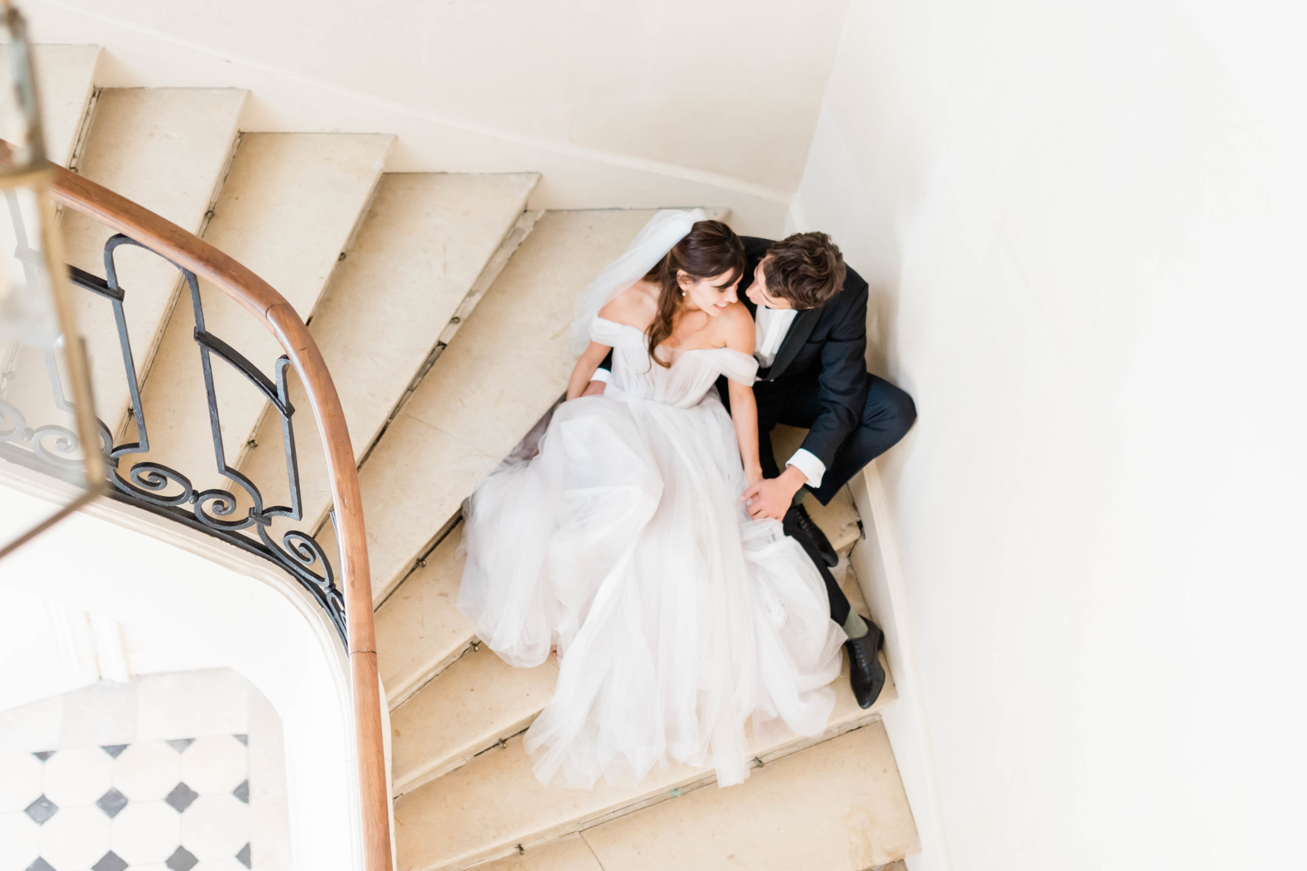bride and groom sitting in a stairwell together as they cuddle and hold hands during their Spring wedding
