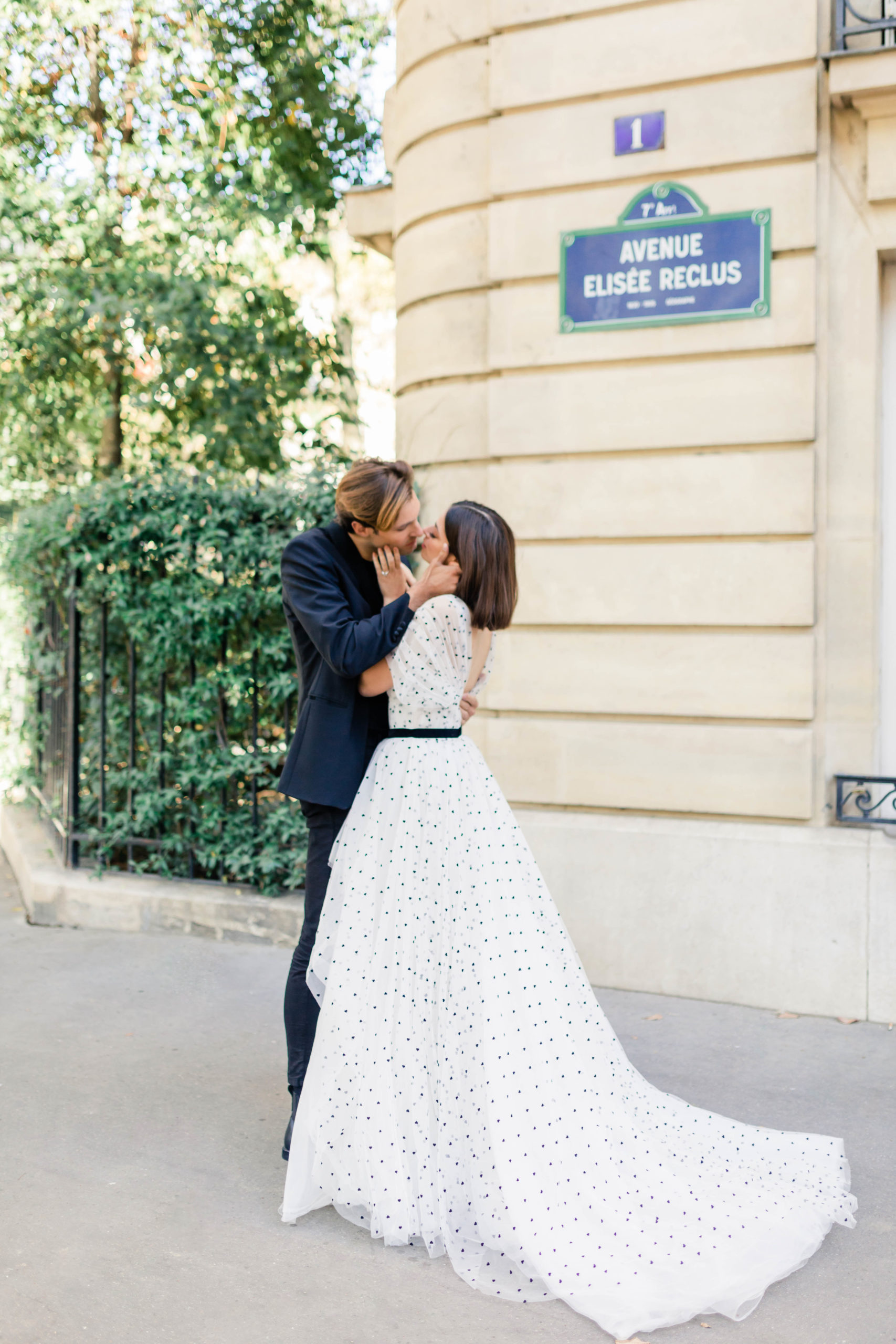 Paris France destination engagement session with man leaning in and kissing a brunette girl as they stand on the side walk together