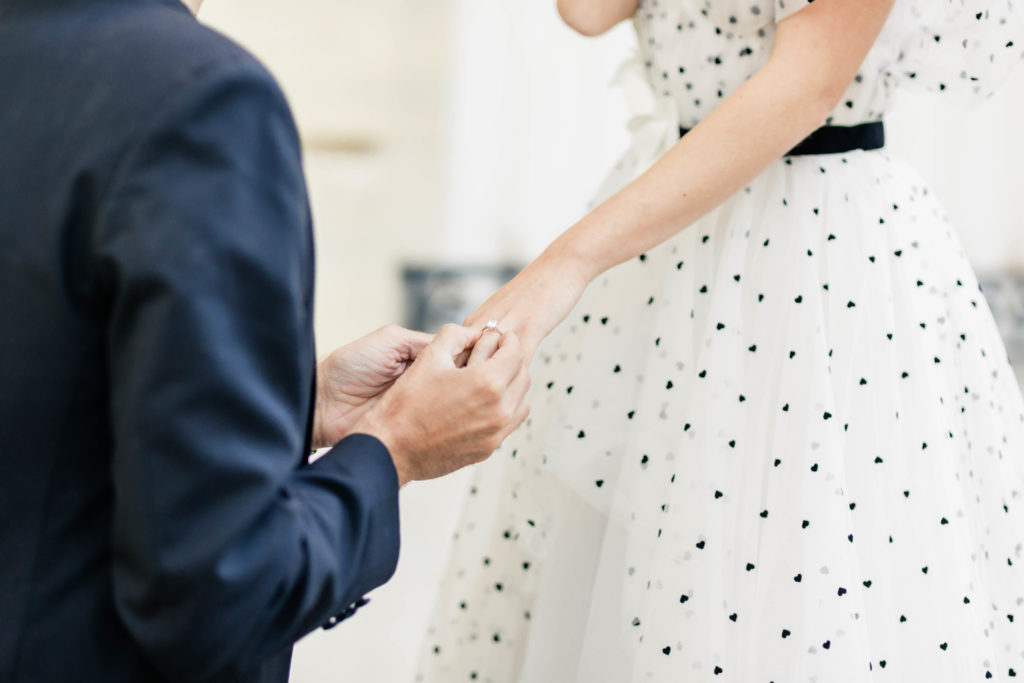 detail shot of man proposing and putting an engagement ring on womans hand