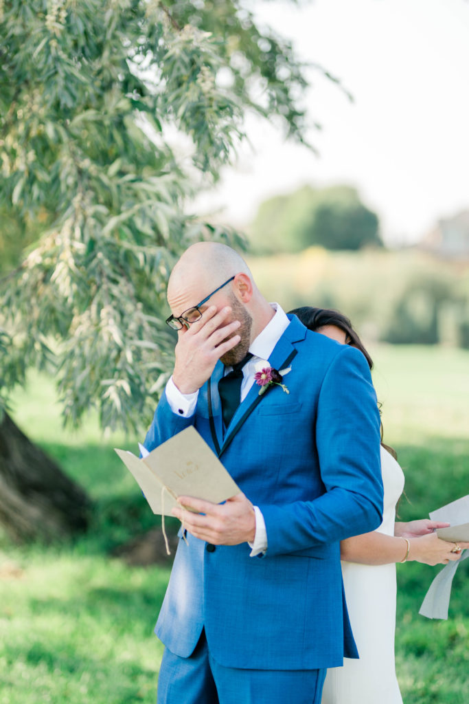 groom getting emotional as he reads his private vows during a summer wedding