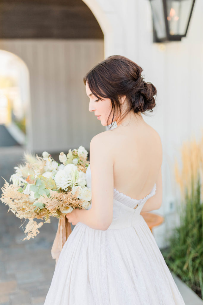 bride holding a neutral floral bouquet on her Boise Idaho wedding day while standning outside of her elegant wedding venue