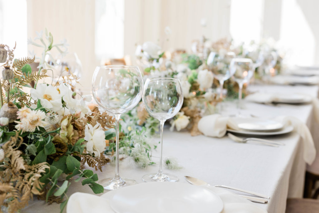 wedding table centerpiece of lush florals and white plates at indoor Boise wedding venue
