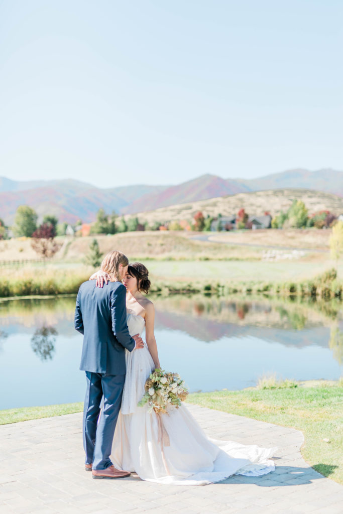 outdoor summer wedding photography with bride and groom in front of a lake on a clear sky summer day