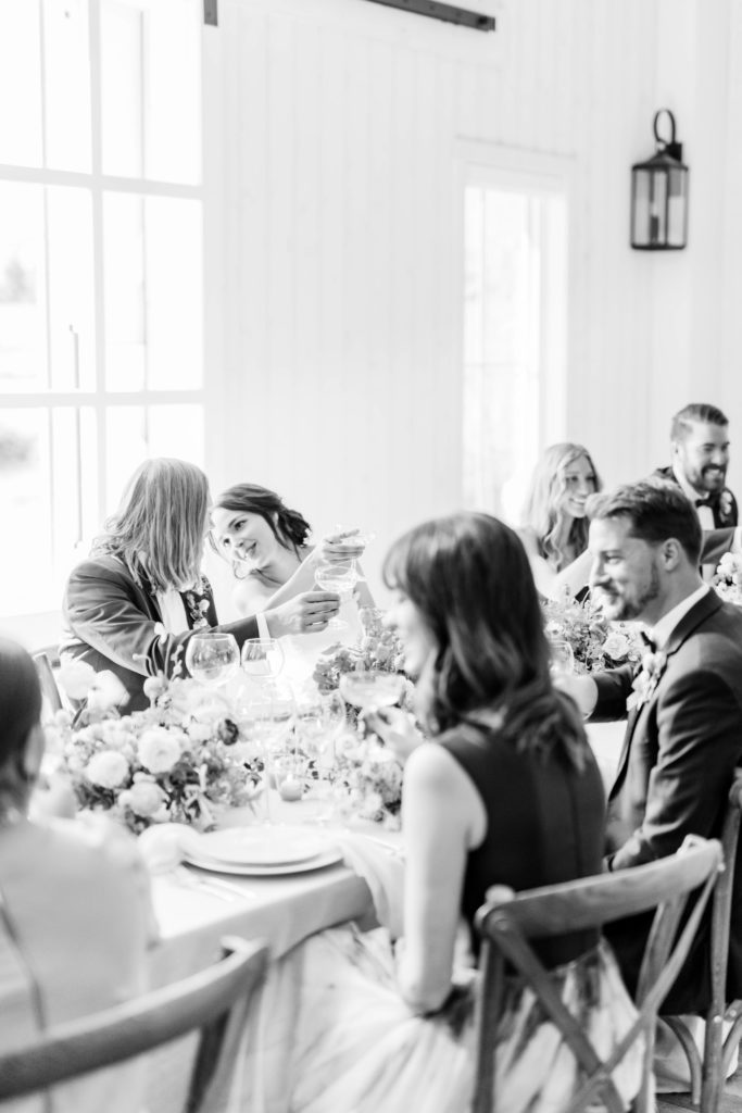 black and white image of bride an groom sitting at a wedding reception table with their guests