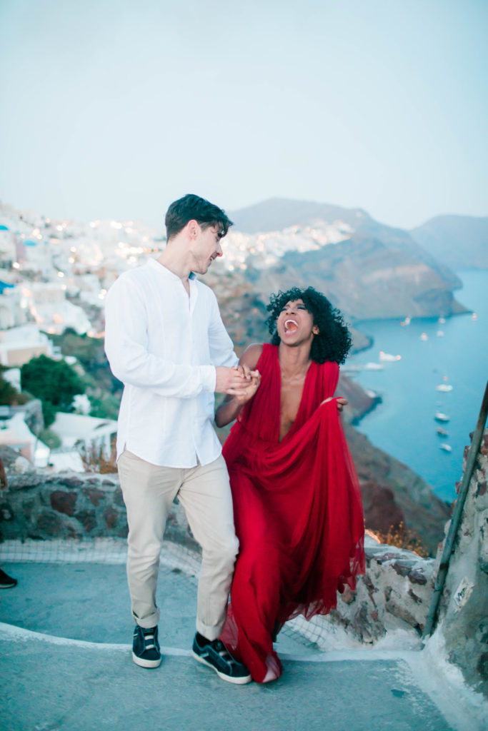 woman laughing as she walks up some stairs with her fiance in Greece for her destination engagement session