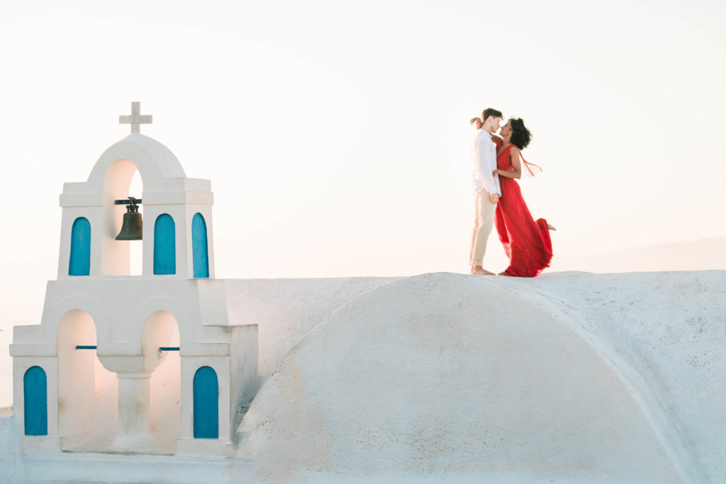 man and woman embracing on top of a roof in Greece during their destination engagement photoshoot 
