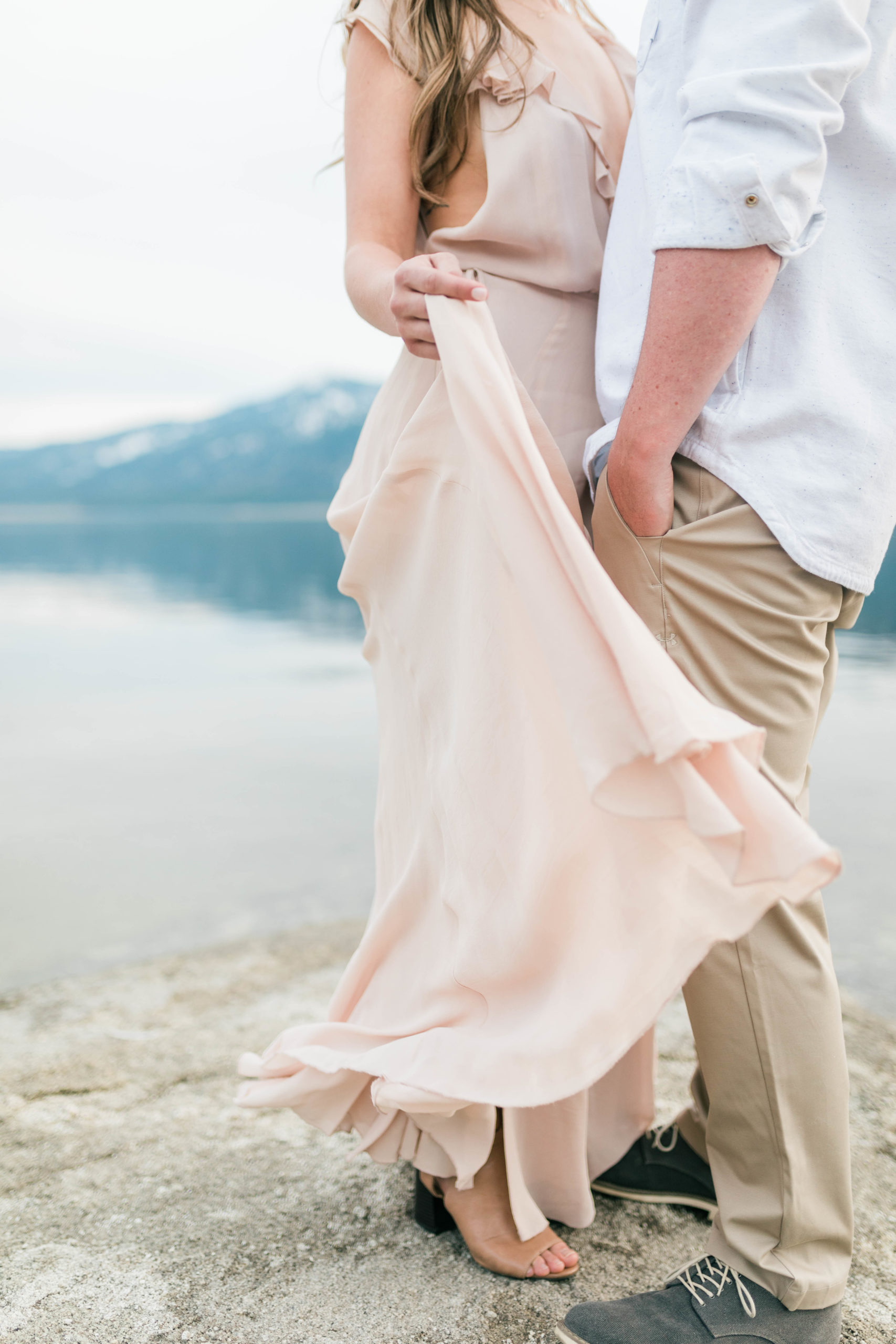 detail shot of blush pink dresses skirt blowing in the wind at a lake engagement session