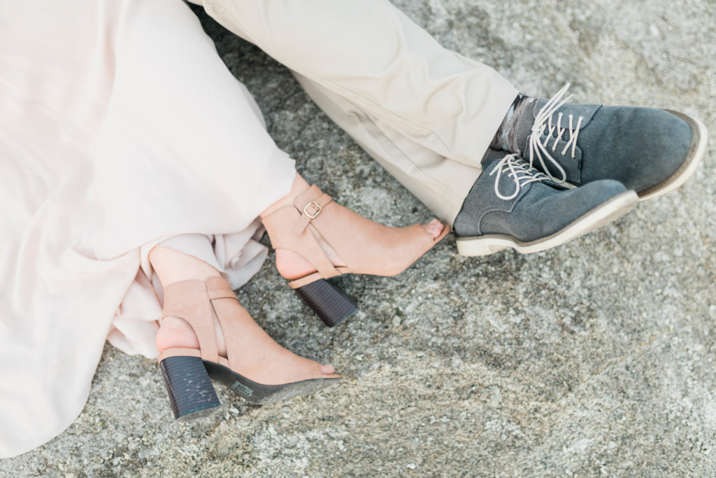 detail shot of man and womans shoes on a lake rock