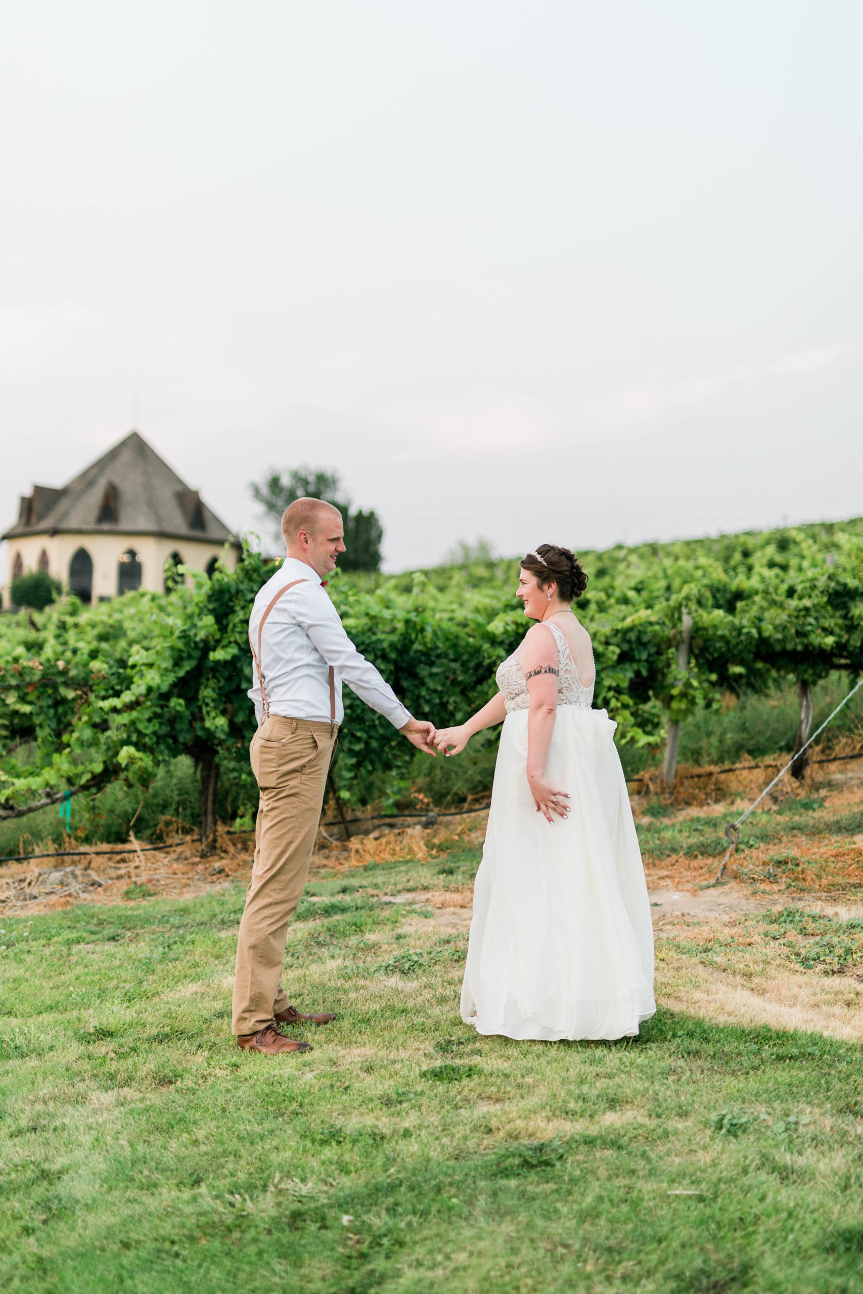 bride and groom holding hands in the middle of a vineyard