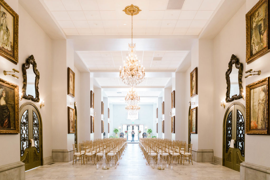 indoor wedding reception in a long hall style ballroom with ornate art hanging on the walls 