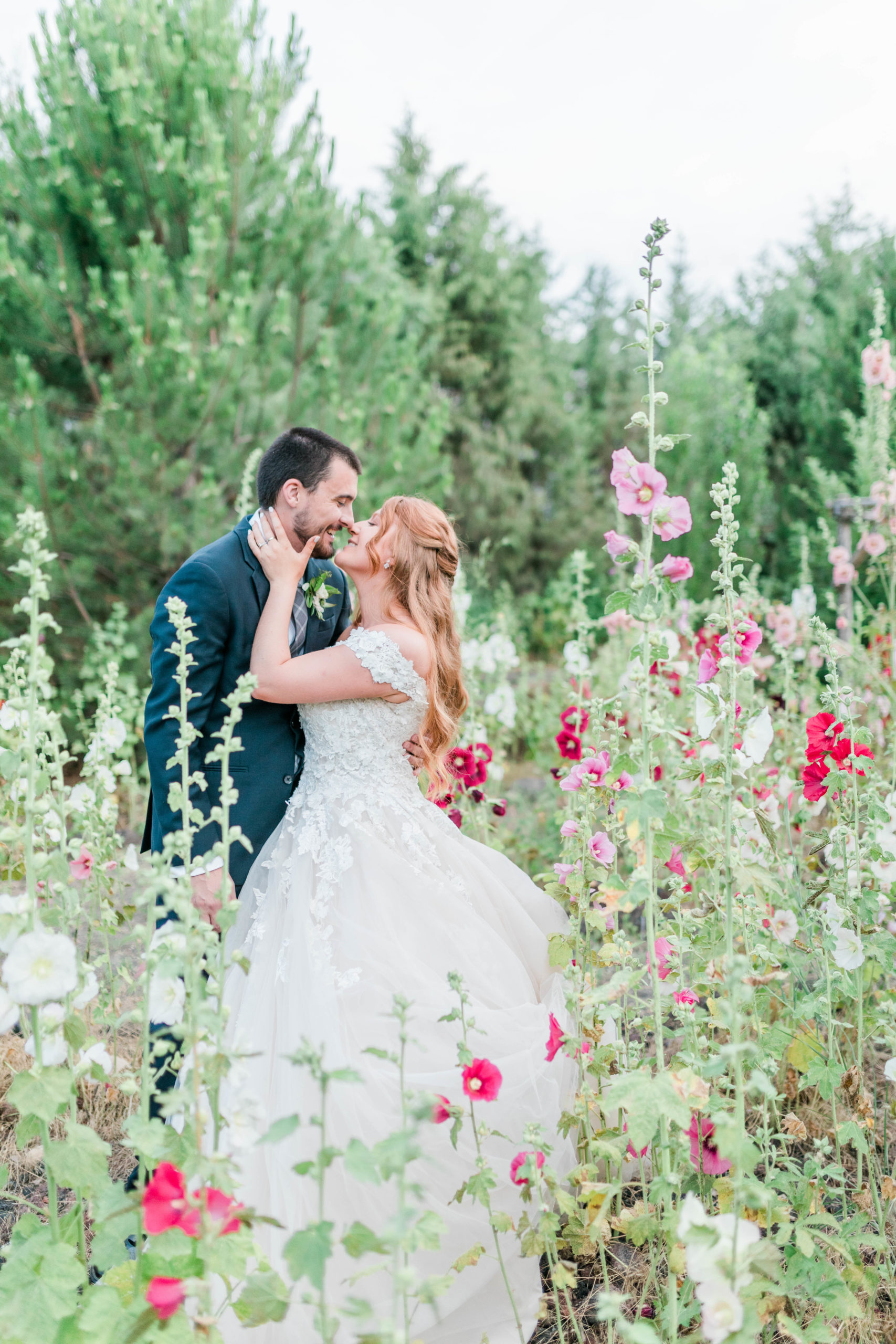 bride and groom standing in a wildflower field together embracing on their wedding day in Boise
