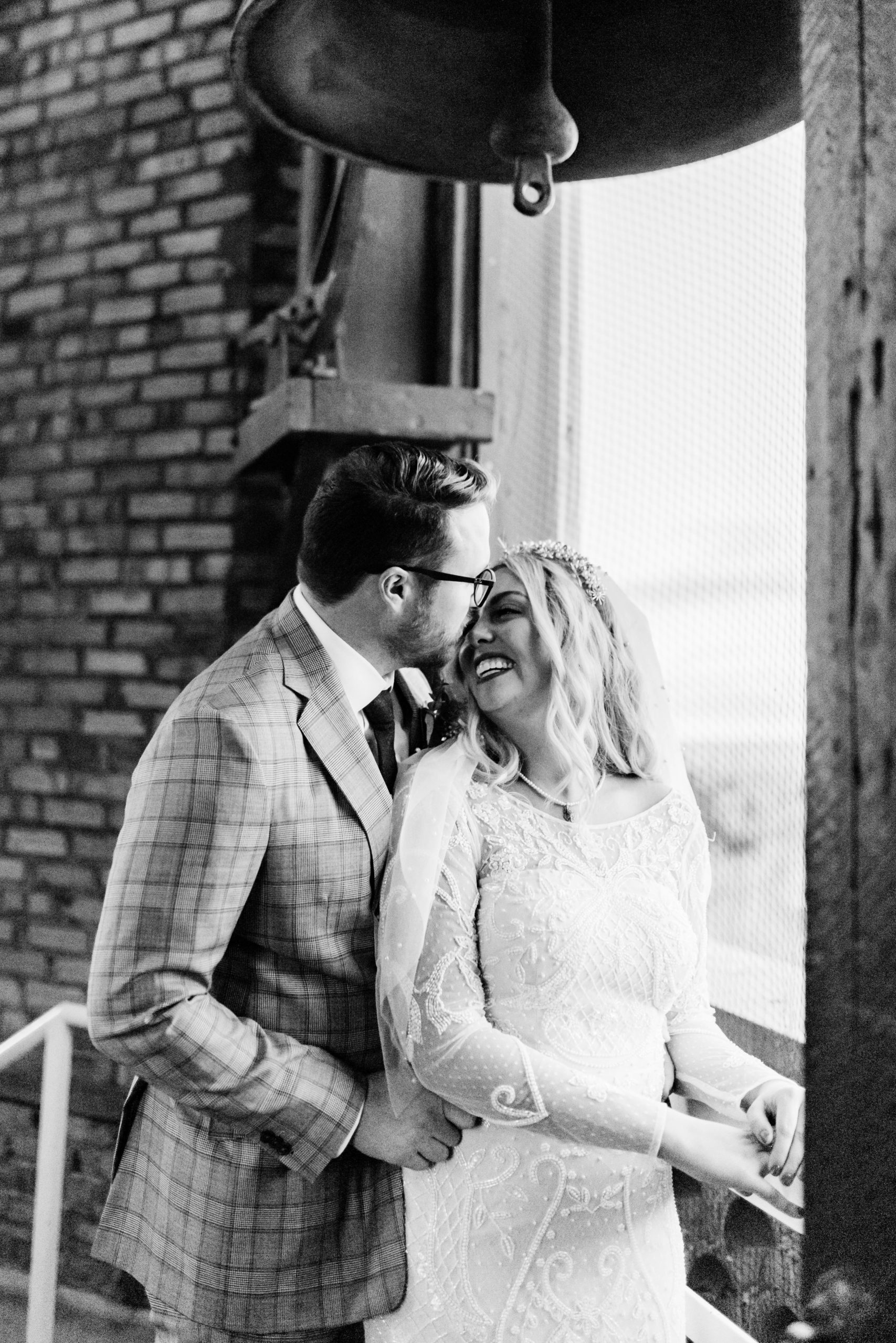 black and white wedding photo of bride and groom sitting together and laughing 