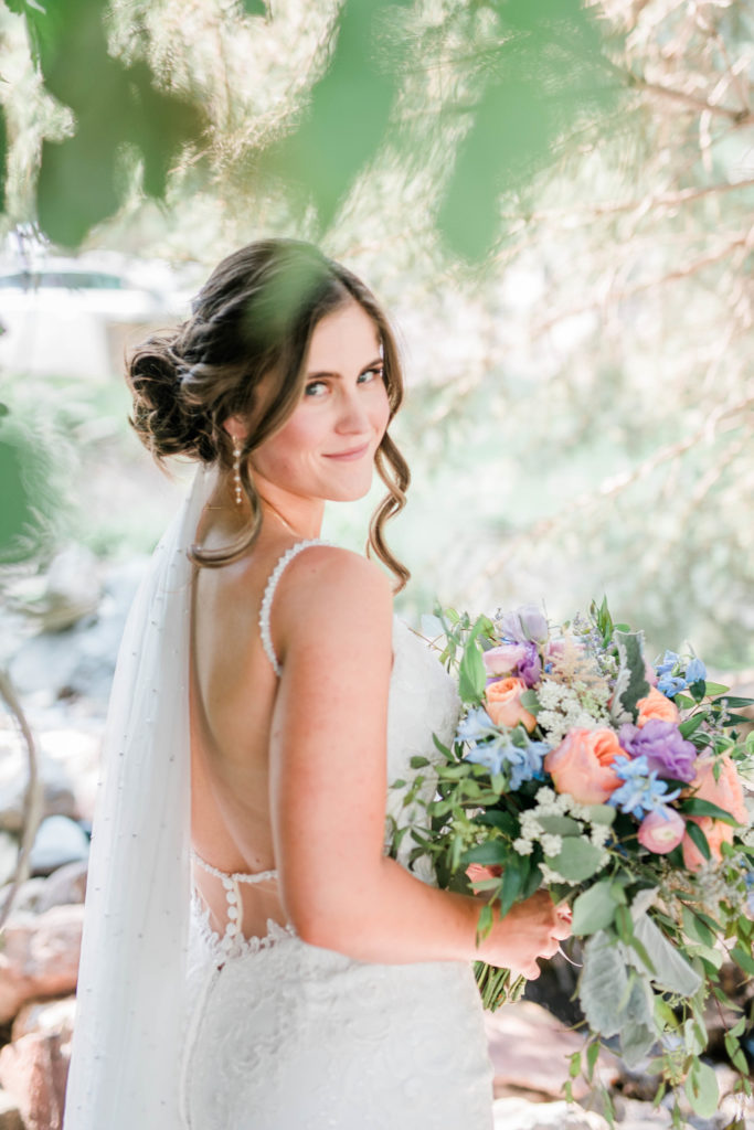 Boise wedding photographer captures modern bride with a low bun and lace wedding gown in a garden with her floral bouquet 