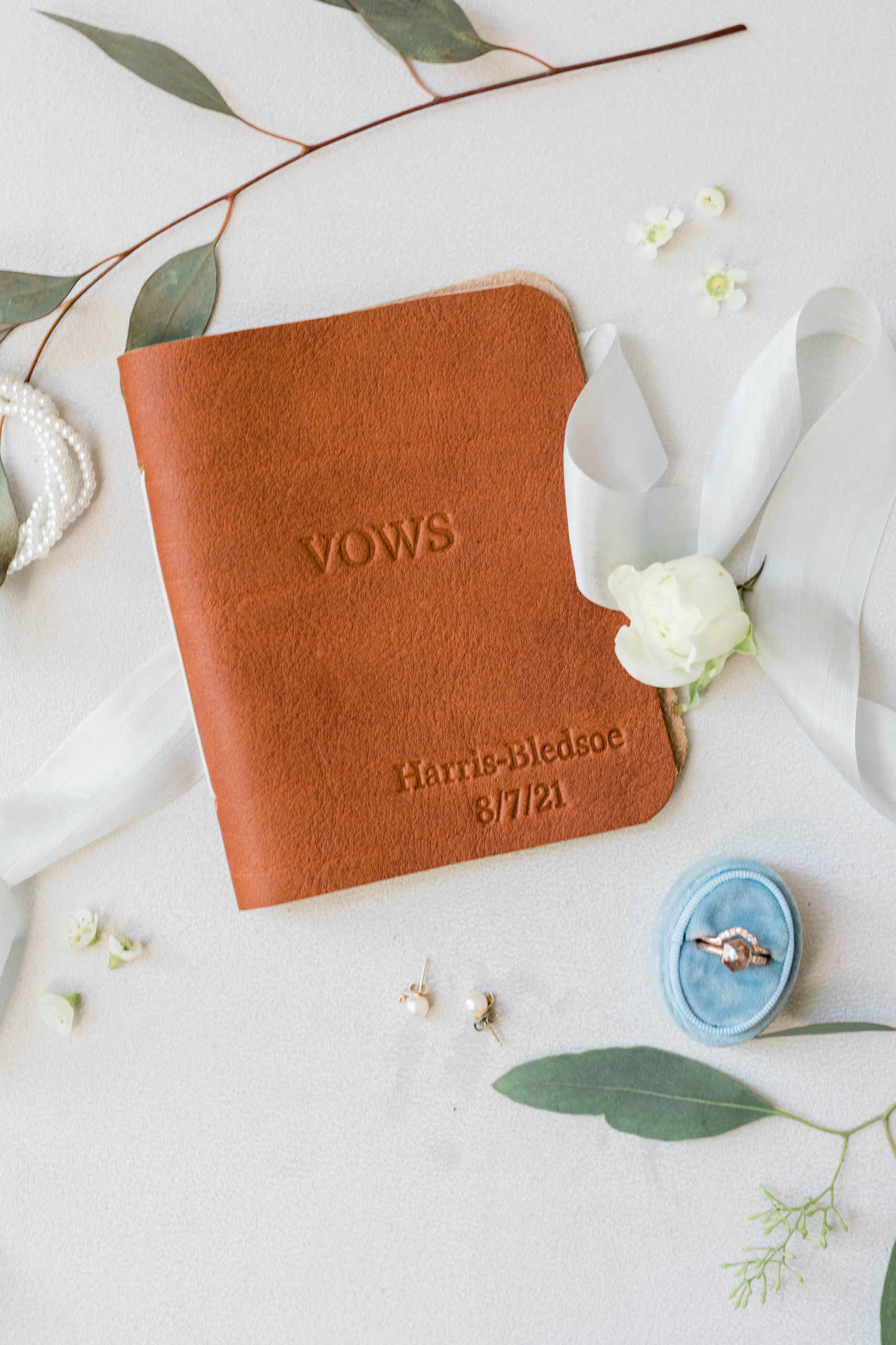light brown leather vow book with florals surrounding it