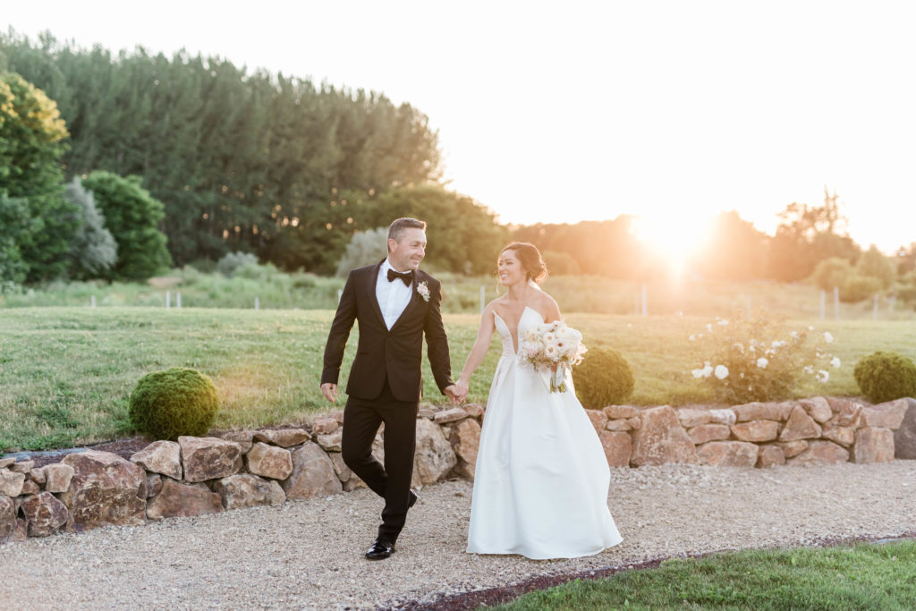 sunset wedding photos in Boise Idaho with bride and groom holding hands and walking down a path for their outdoor wedding 
