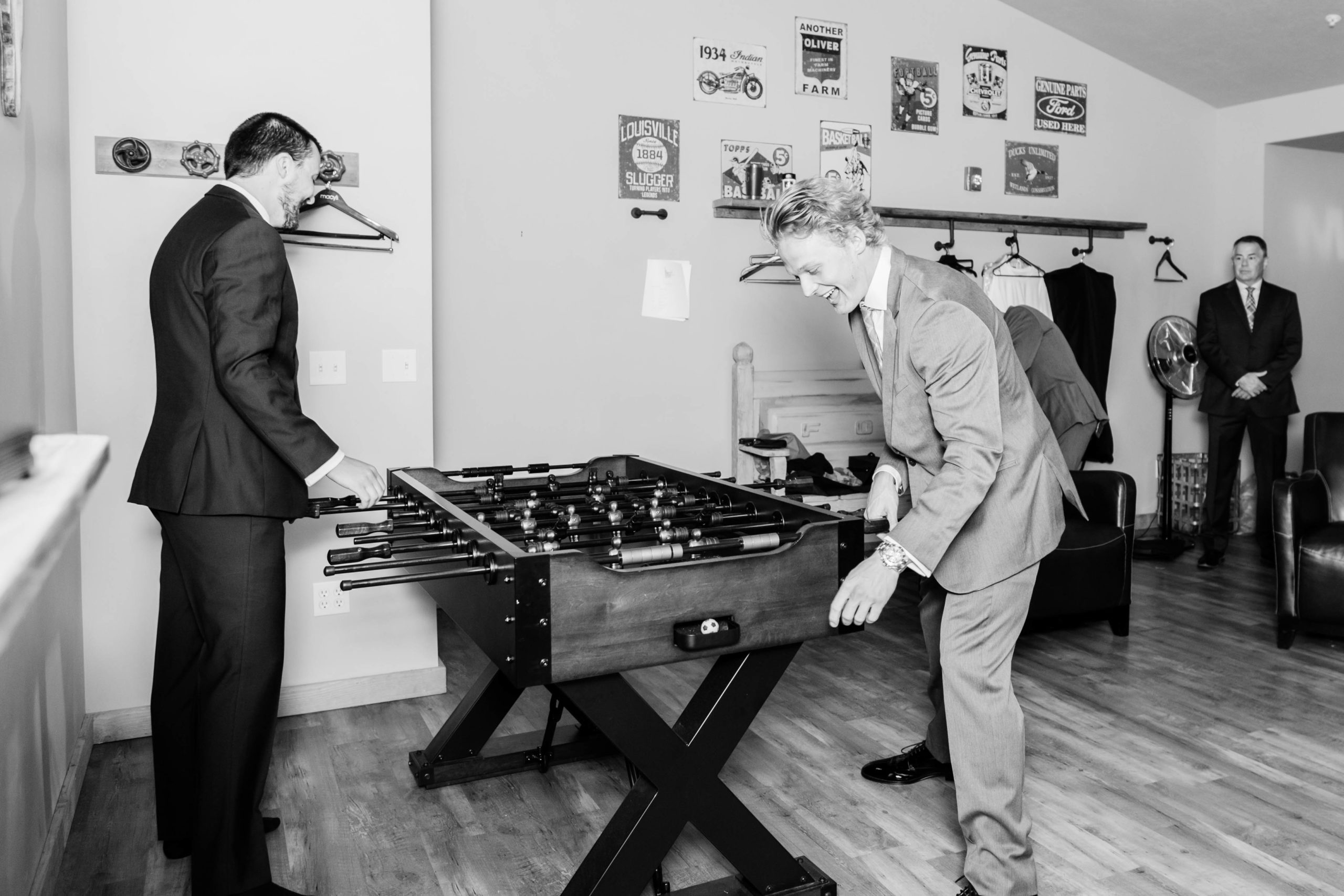 groom and his groomsmen playing foosball as they wait for the ceremony after getting ready at Still Water Hollow wedding venue