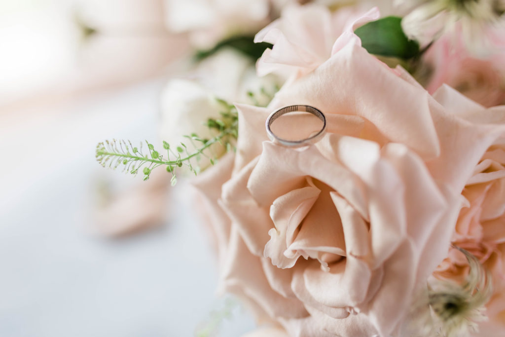 wedding ring sitting on a light pink rose for wedding photos taken by Boise wedding photographer