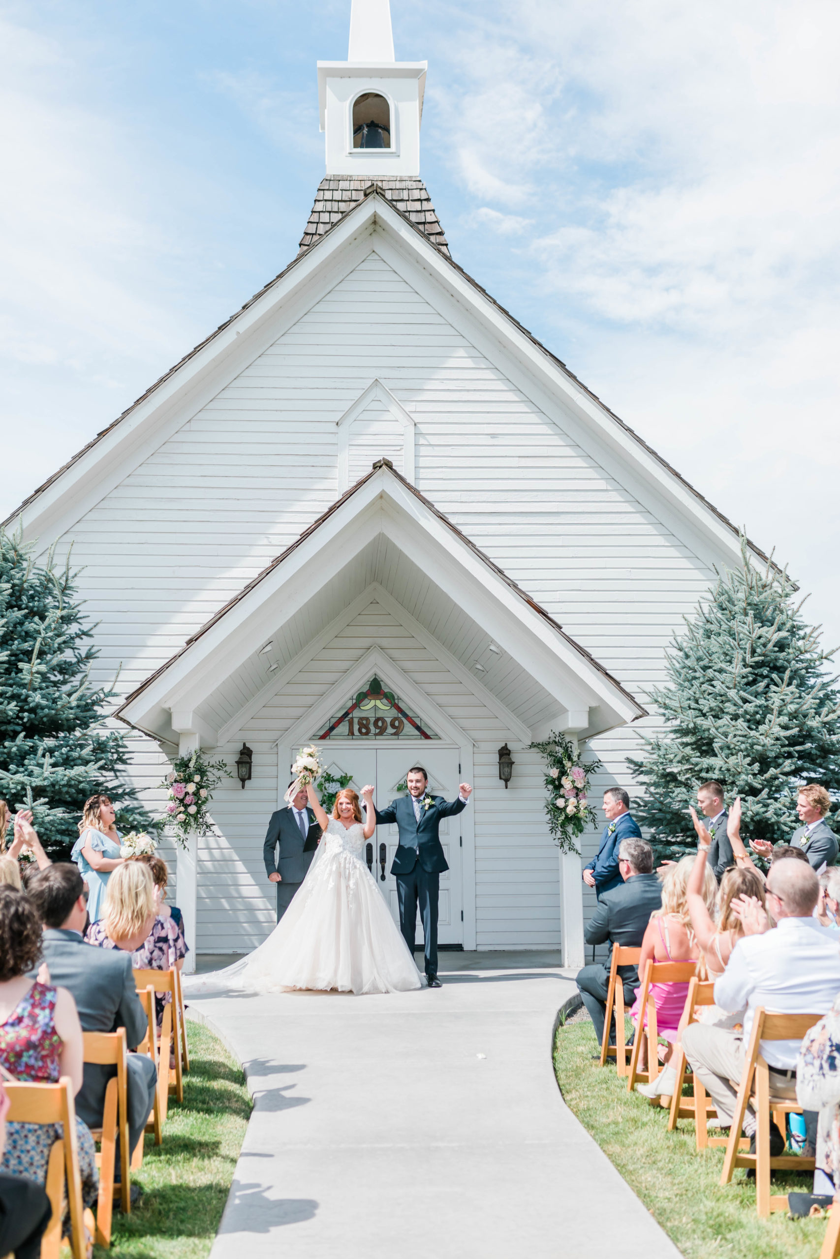 outdoor ceremony with bride and groom holding ands and walking out of the ceremony space with their arms in the arm in celebration