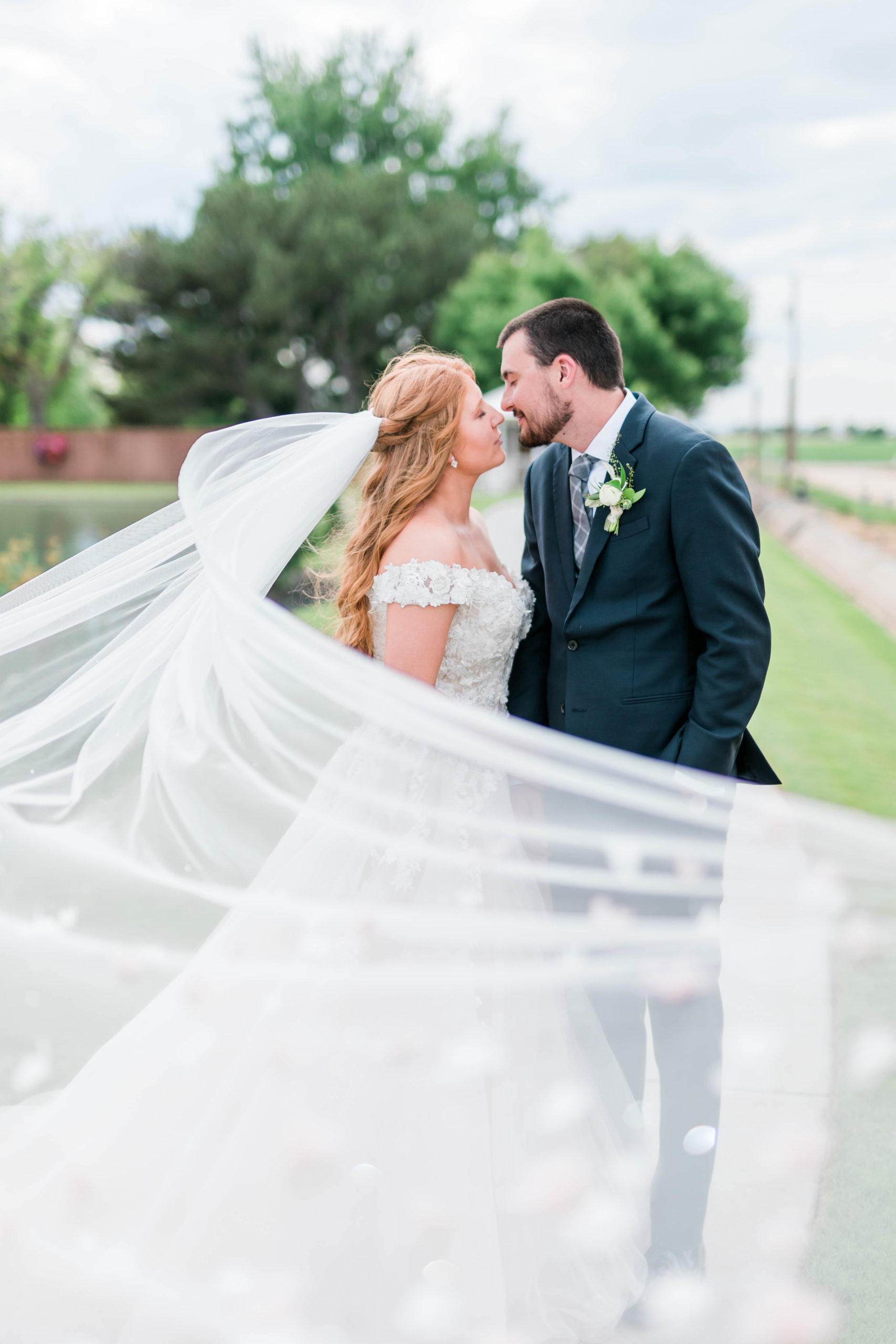 Boise bridal photos with bride and groom kissing as the brides veil blows in the wind captured by Boise Wedding Photographer