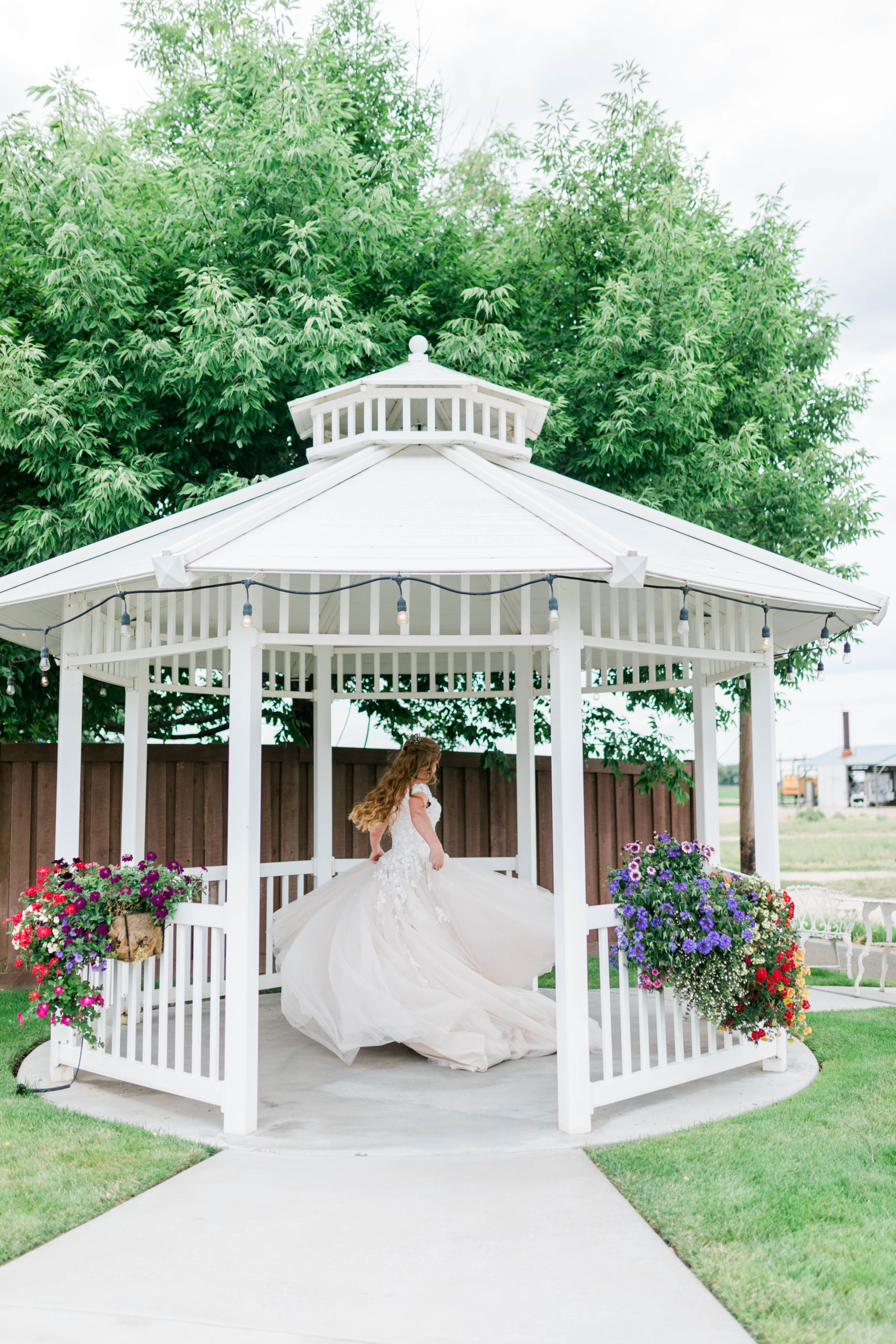 bride twirling her wedding dress in a white gazebo captured by Boise wedding photographer