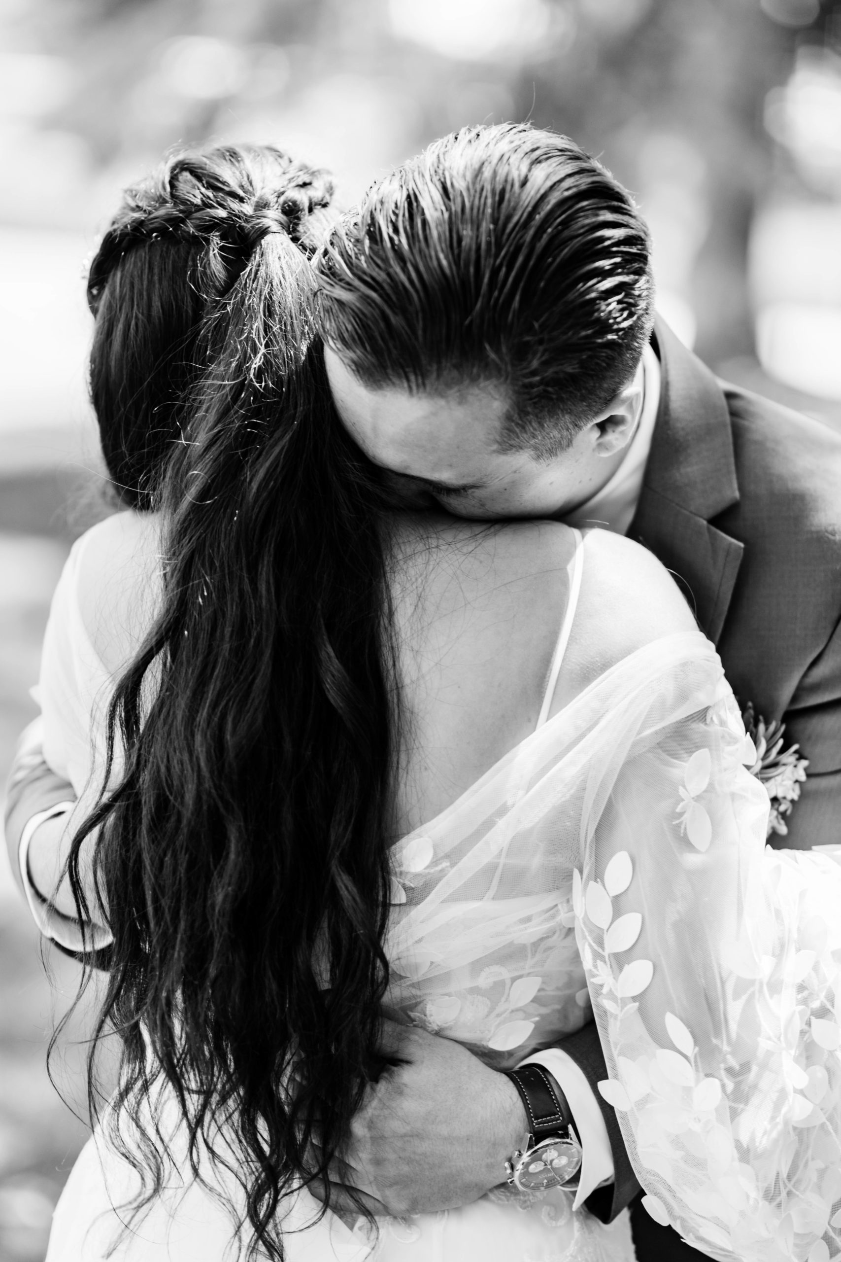 black and white image of bride and groom hugging as the groom cries into the brides shoulder