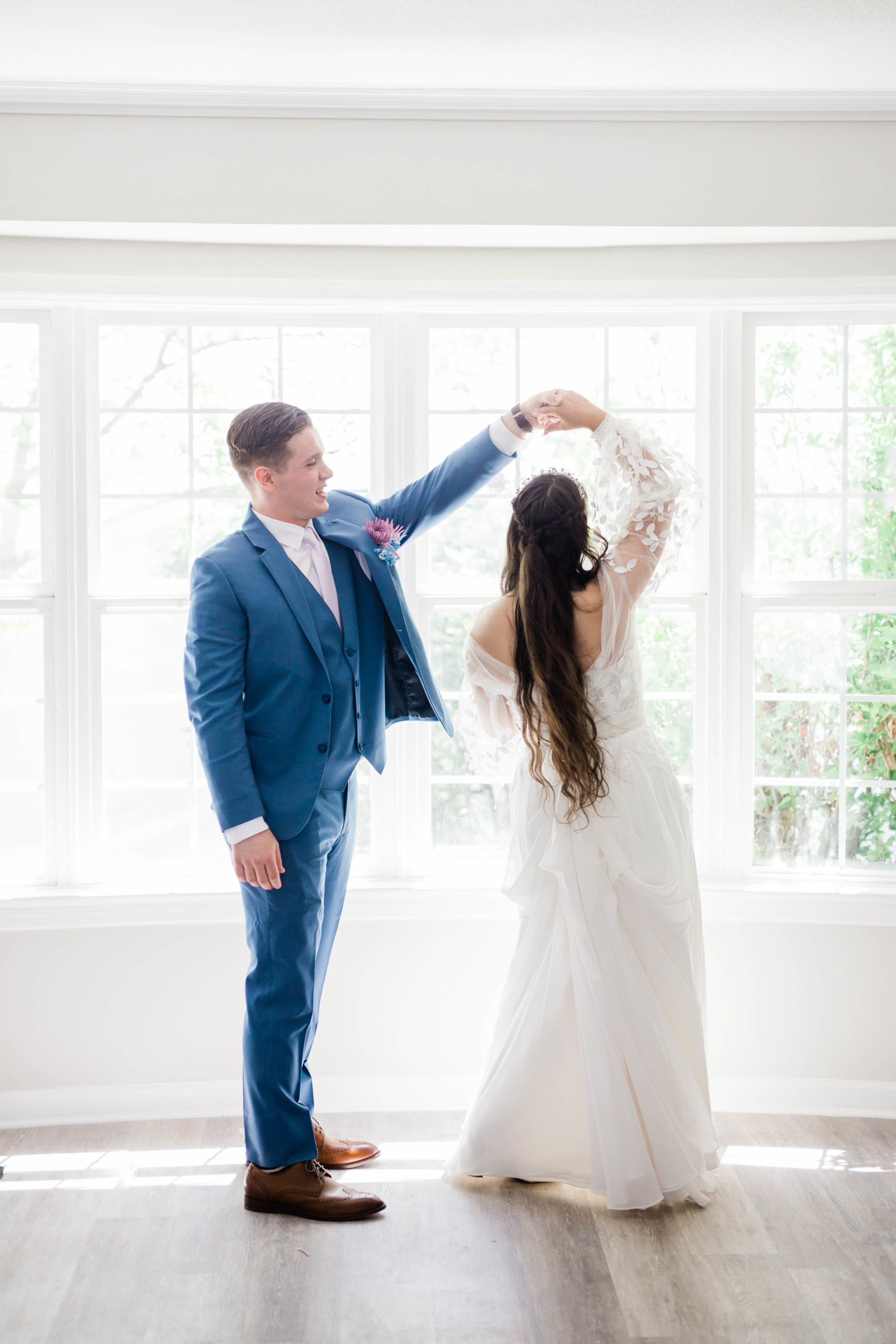 bride adn groom dancing in a beautiful white bay window
