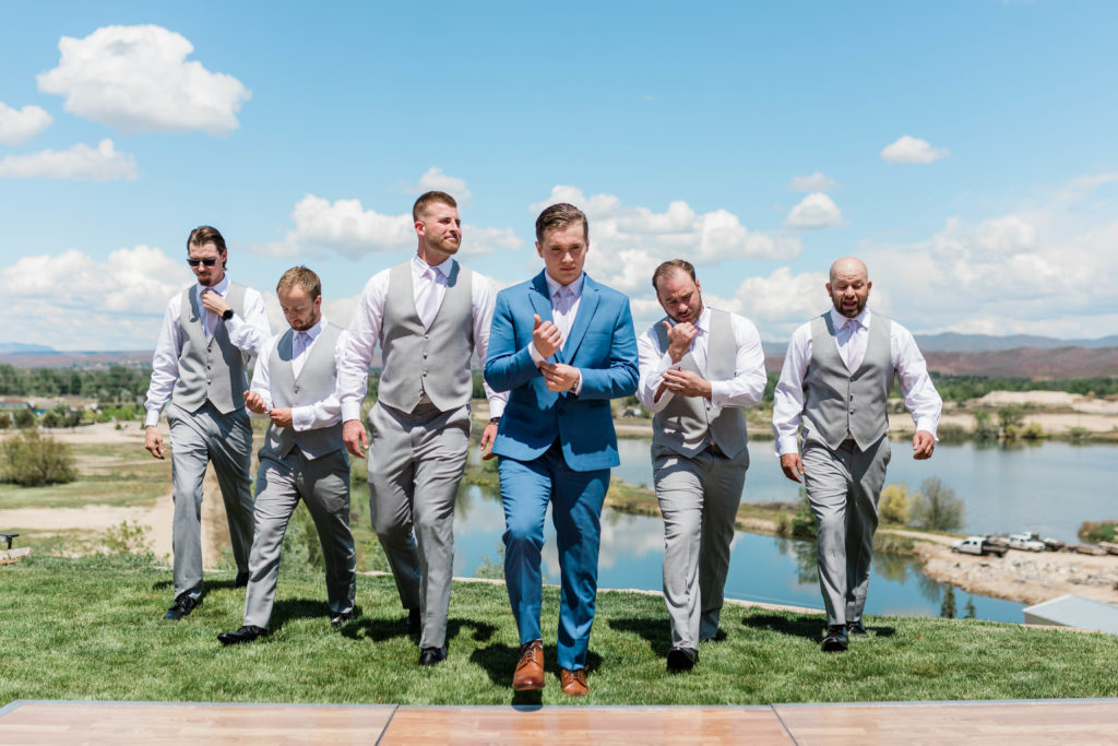 groom and his groomsmen walking together as fixing their cuffs 