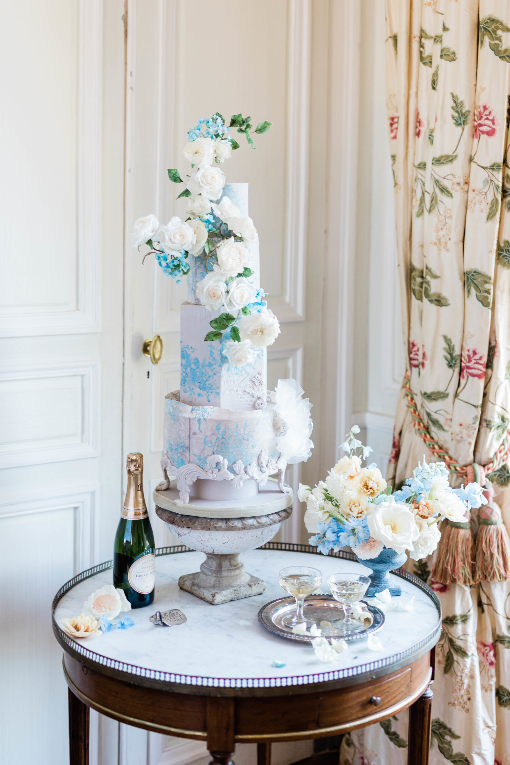 three tiered blue and white wedding cake with florals at destination wedding in Paris