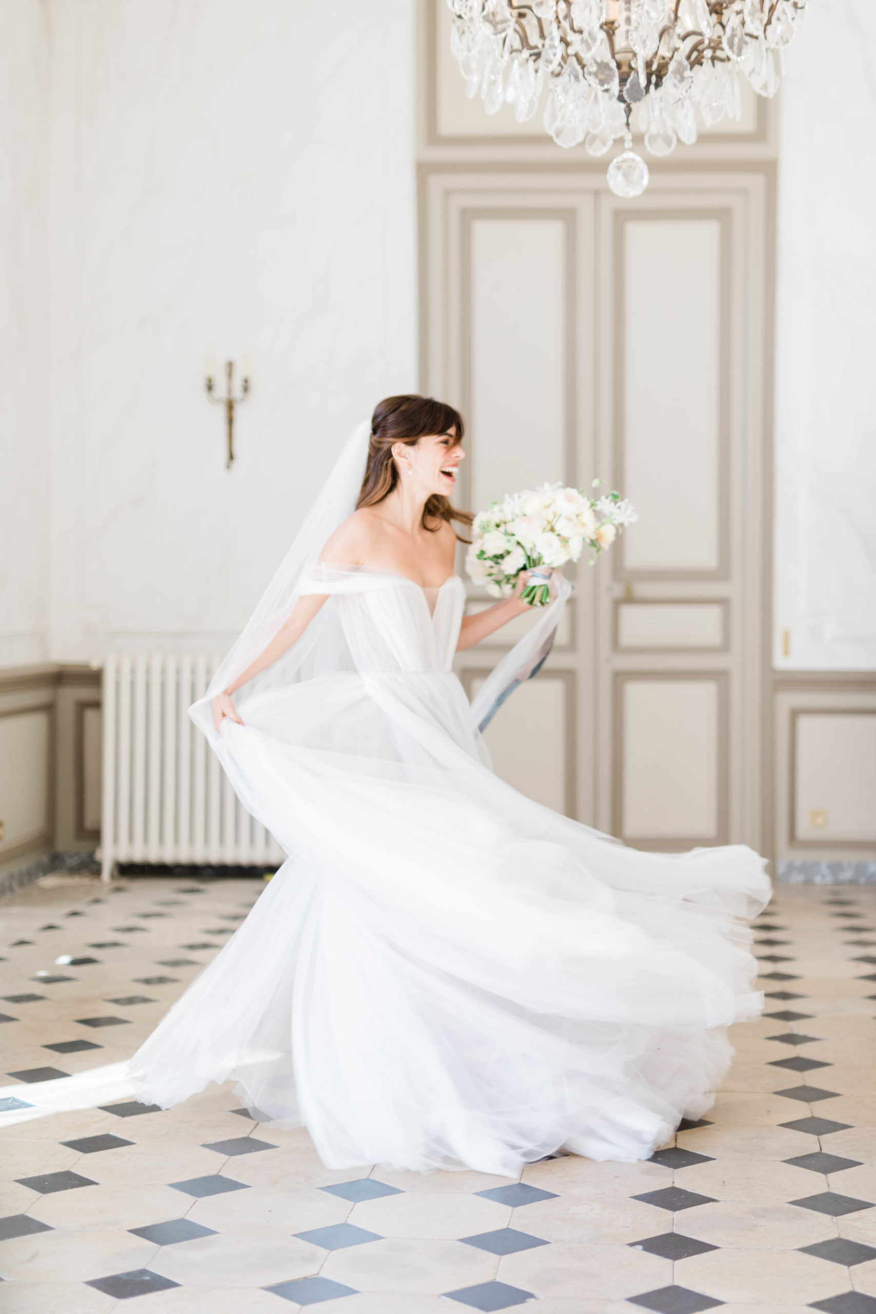 bride dancing in her wedding dress in a castle hall while holding her floral bouquet