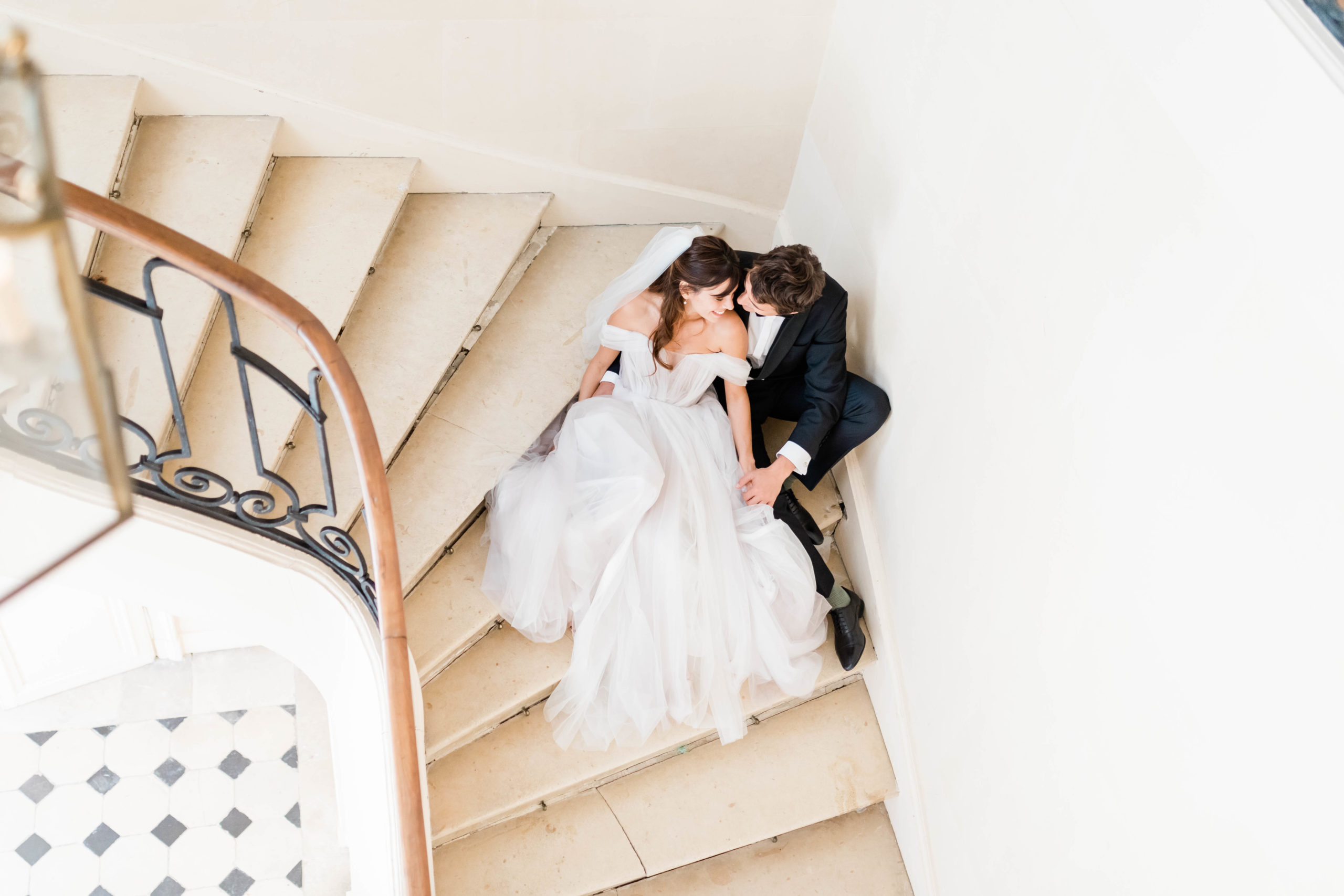 bride and groom sitting on stairs after intimate first look in Paris wedding