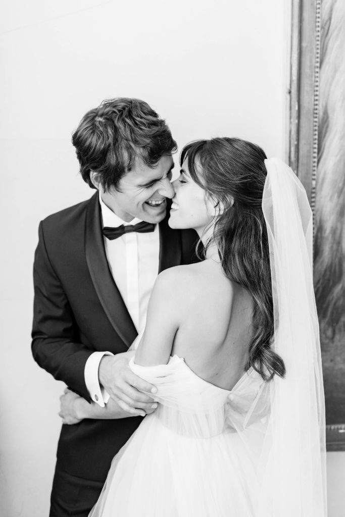 bride and groom kissing in black and white portrait before outdoor wedding ceremony