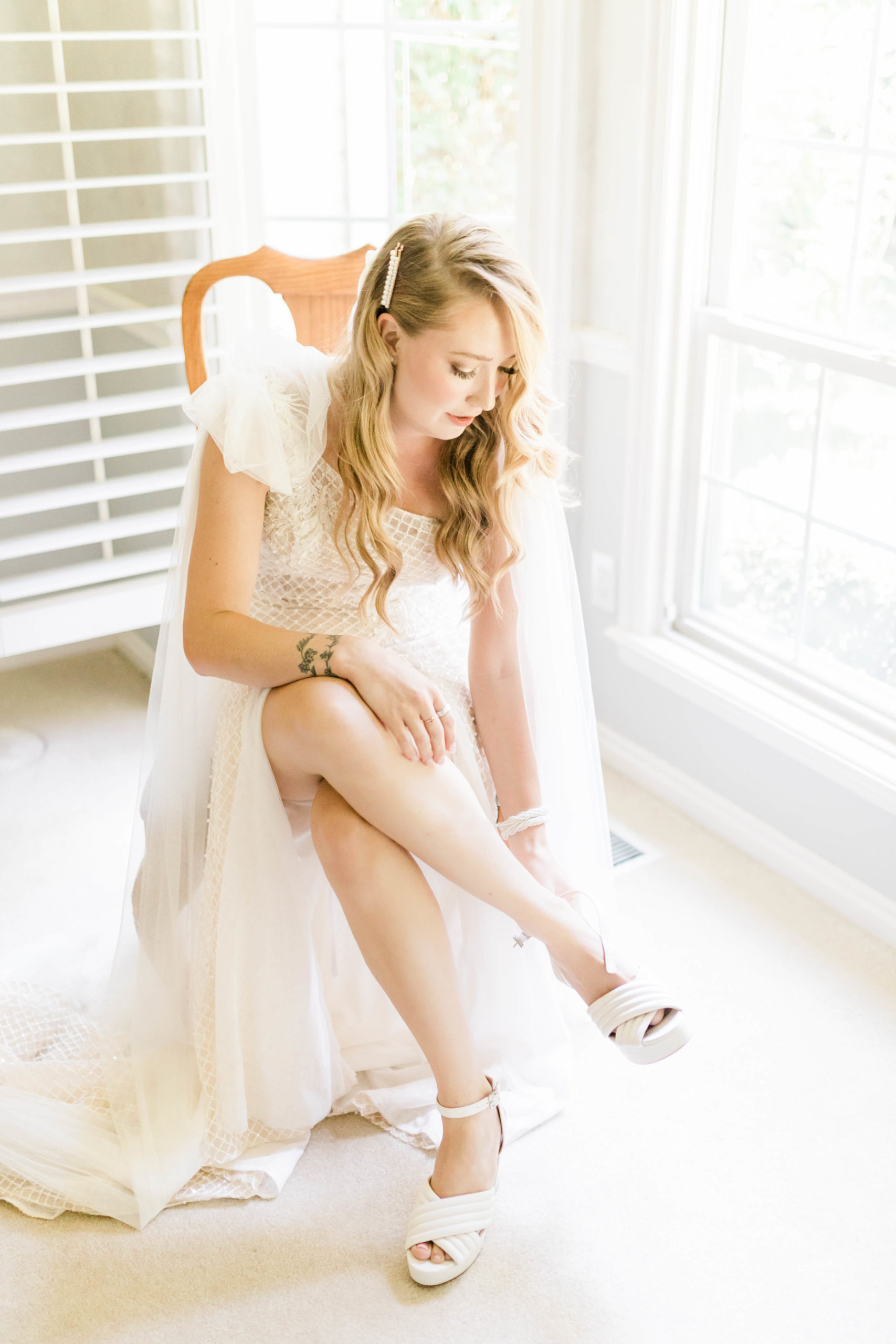 Boise wedding with bride putting on her wedding shoes as she sits in front of a window